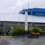 Imagem entrada da Delegacia de Policia, ao fundo aparecem pessoas na entrada