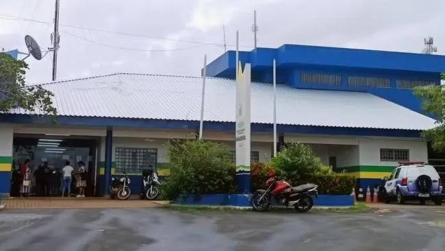 Imagem entrada da Delegacia de Policia, ao fundo aparecem pessoas na entrada