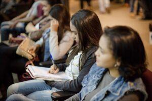 A imagem mostra alunos sentados estudando