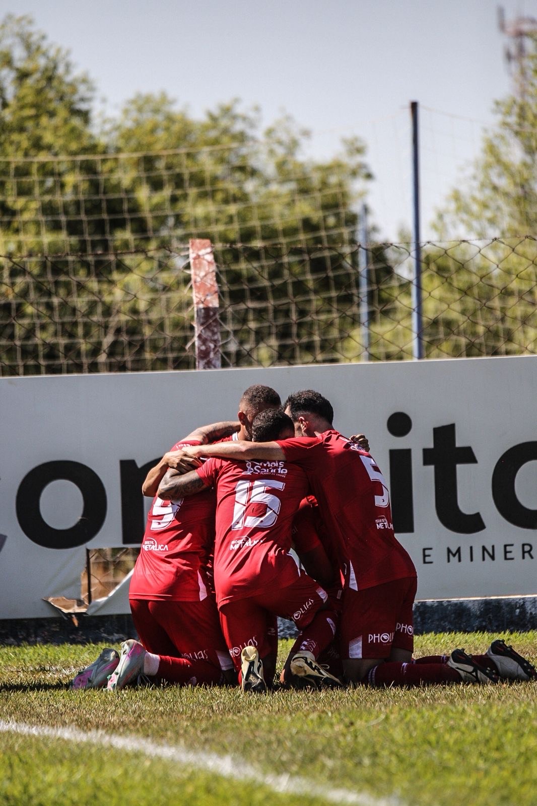 Imagem Jogadores abraçados e ajoelhados em campo comemorando o gol da Vitoria