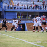 Imagem jogadores Anápolis x Botafogo-PB, um jogador do Anápolis chuta a bola e jogadores dos dois times estão dentro da área.
