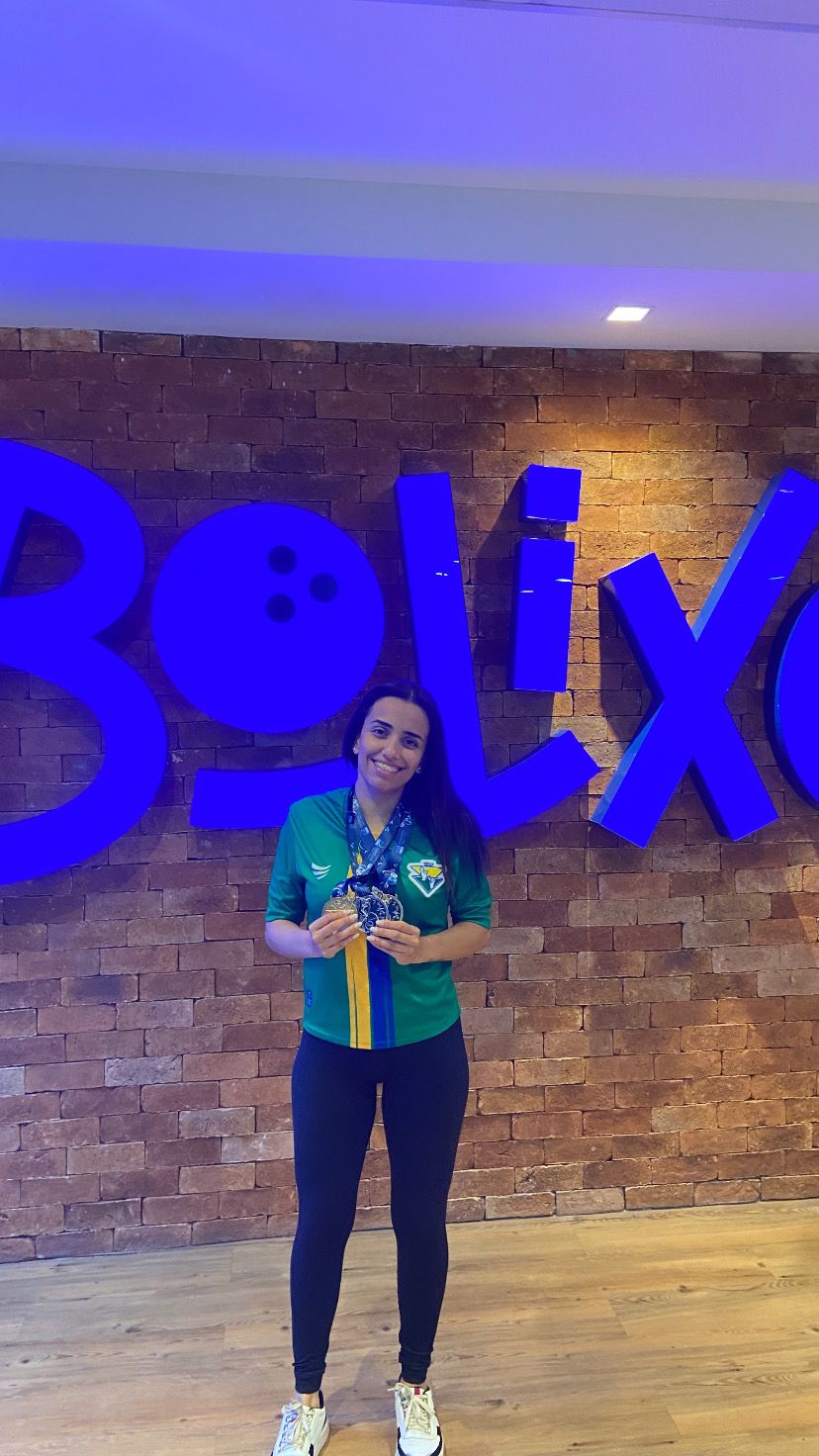 Imagem atleta Aléxia sorrindo, segurando uma medalha