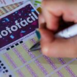 Imagem uma mão segurando uma caneta e preenchendo jogo da lotofacil