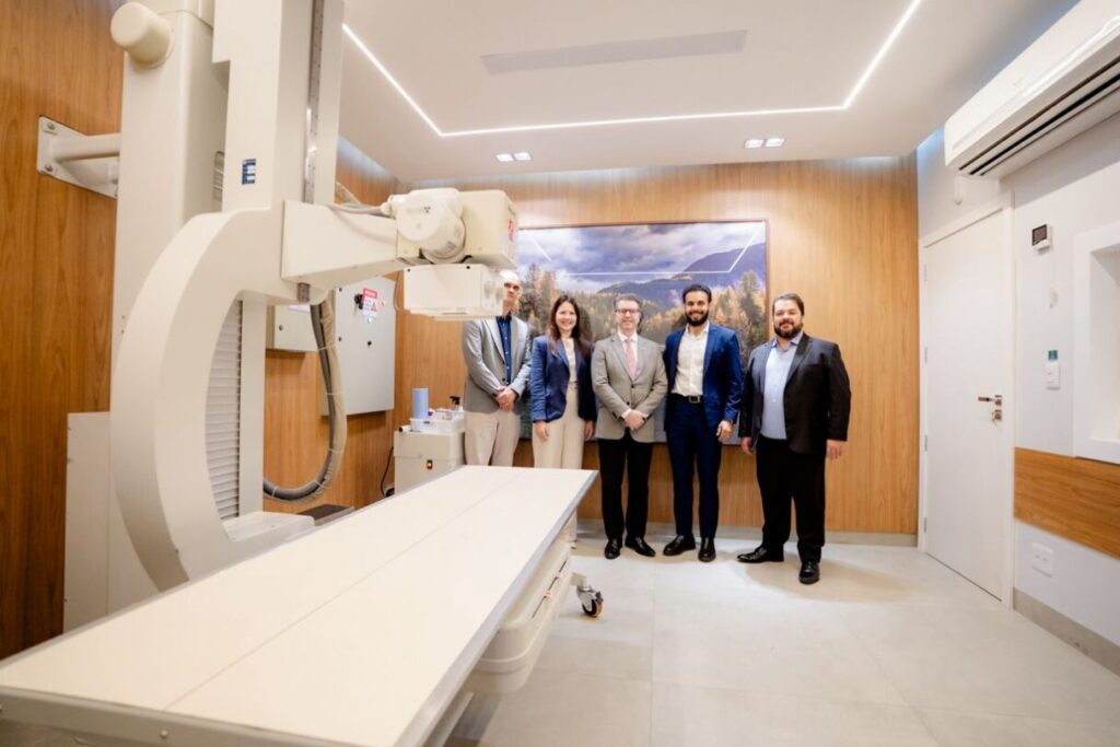 Imagem equipamento no hospital ao fundo pessoas posam para foto