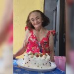 Imagem Idosa Desaparecida, ela está sorrindo com um bolo de aniversário na mesa