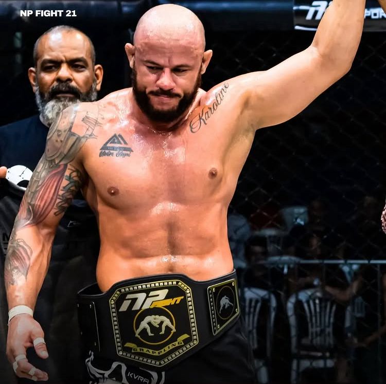 Imagem Junior Magal com o braço erguido e com o cinturão