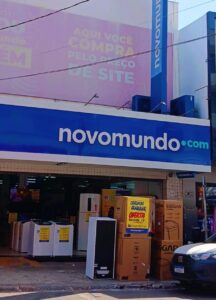 Imagem fachada Loja Novo Mundo Centro Anápolis, na porta estão eletrodomésticos com cartaz de venda, Geladeira, tanquinho, fogão e outros