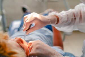 Imagem atendimento odontológico, dentista coloco material na boca do paciente