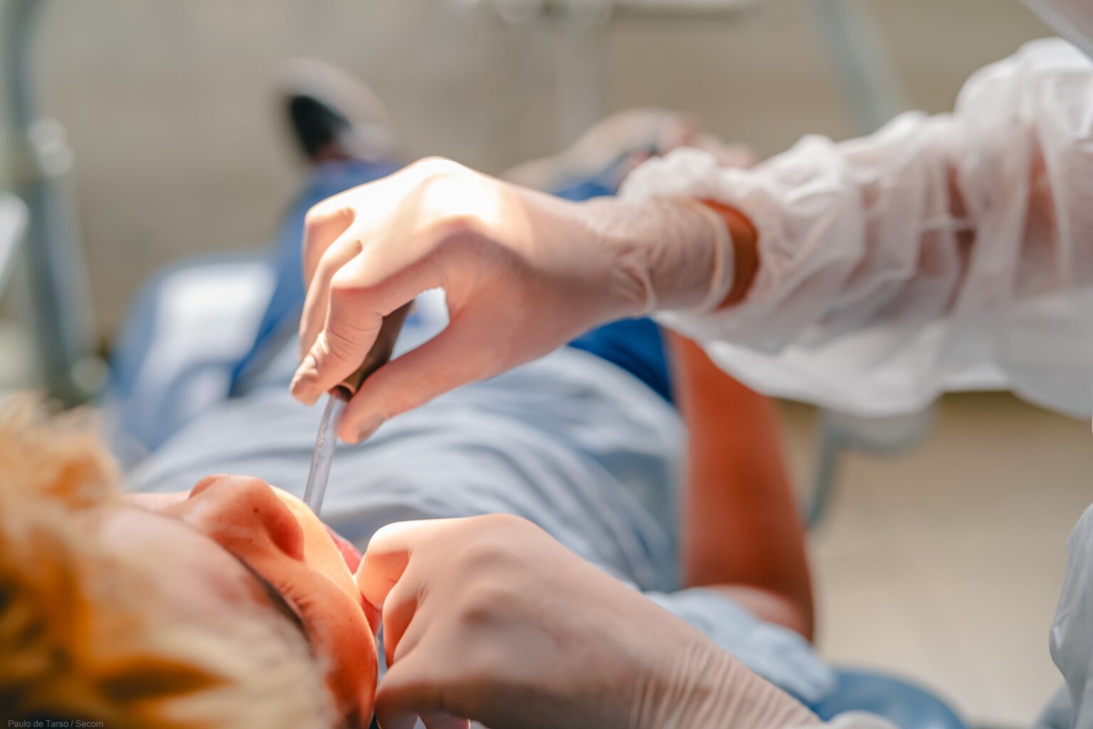 Imagem atendimento odontológico, dentista coloco material na boca do paciente