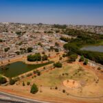Imagem aérea Parque da Vila Jaiara, tem um lago no meio casas e arvores ao fundo
