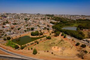 Imagem aérea Parque da Vila Jaiara, tem um lago no meio casas e arvores ao fundo