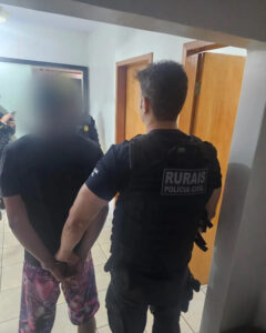Imagem homem preso pela Policia Civil de Goiás, ele está algemado e conduzido pelo policial