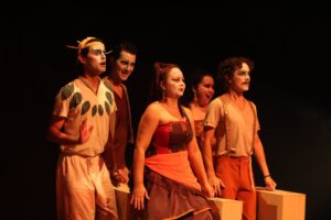 Imagem atores com rosto pintado em cima do palco no Teatro