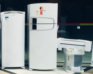 Imagem geladeiras brancas uma menor e outra maior e um ar condicionado