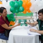 Imagem mulher e homem em uma mesa, ele está entregado um papel na mão dela