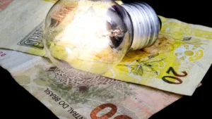 Imagem lâmpada de luz em cima de duas notas, uma de vinte e outra de cinquenta reais
