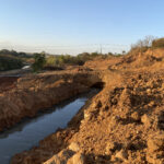 Imagem esgoto escorrendo no meio da terra em região rural