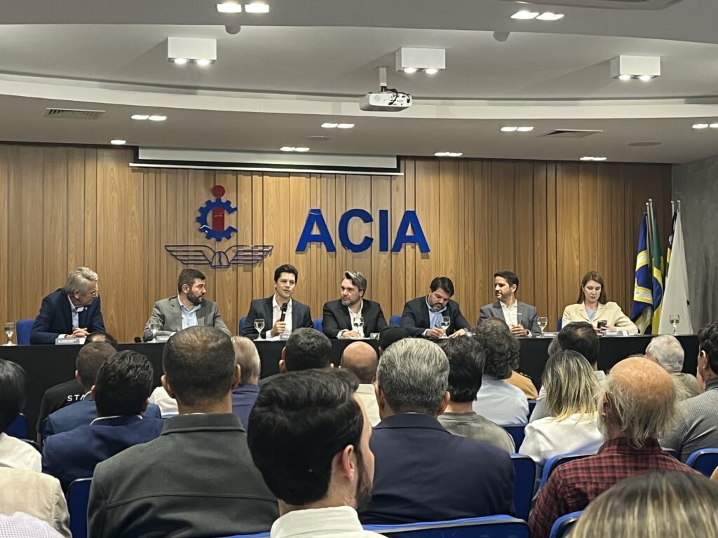 Imagem Daniel Vilela na ACIA, ele está com microfone e tem pessoas ao lado