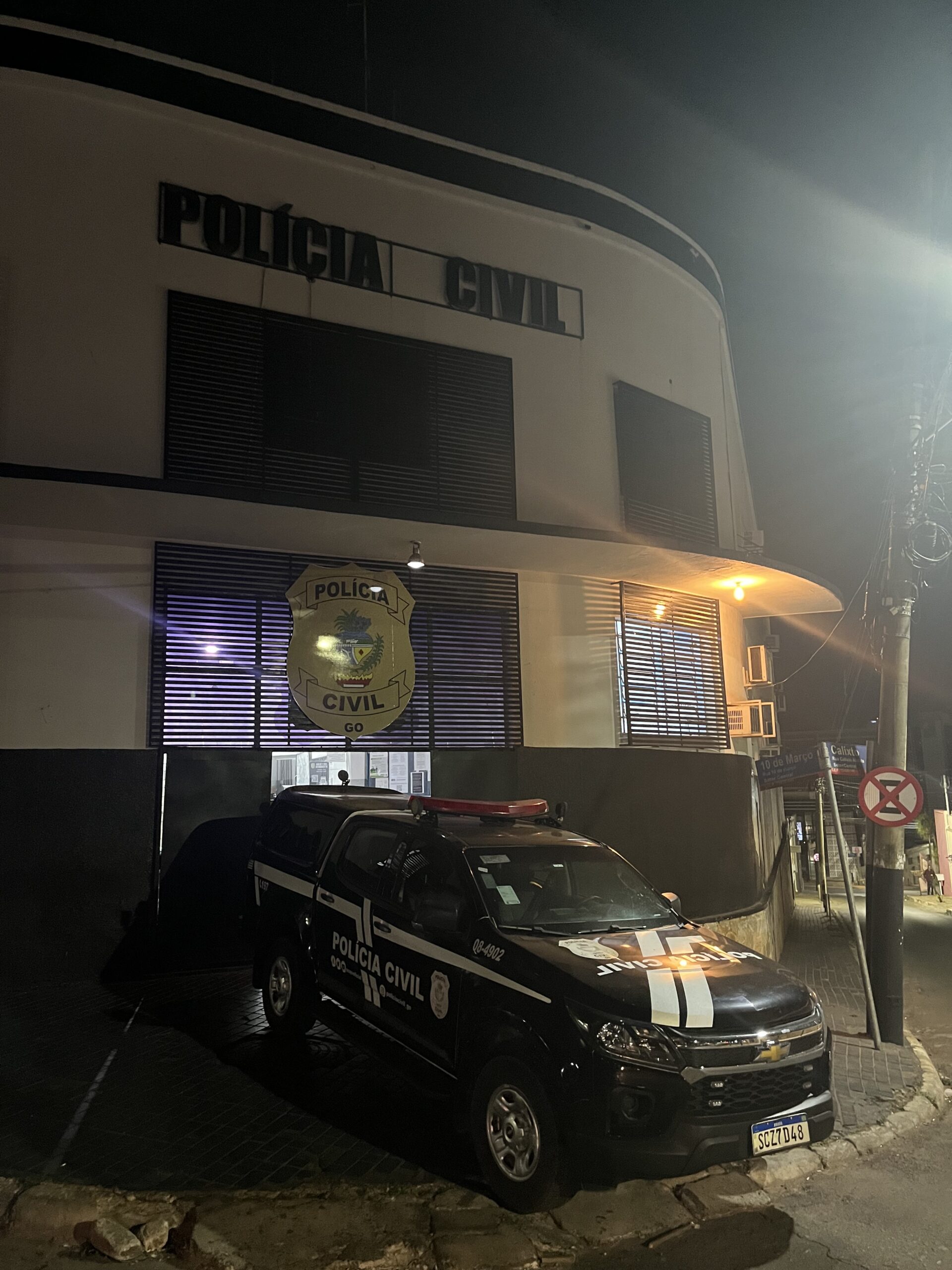 Imagem 1º DP Delegacia Geral, tem uma viatura da Policia Civil na porta e está a noite