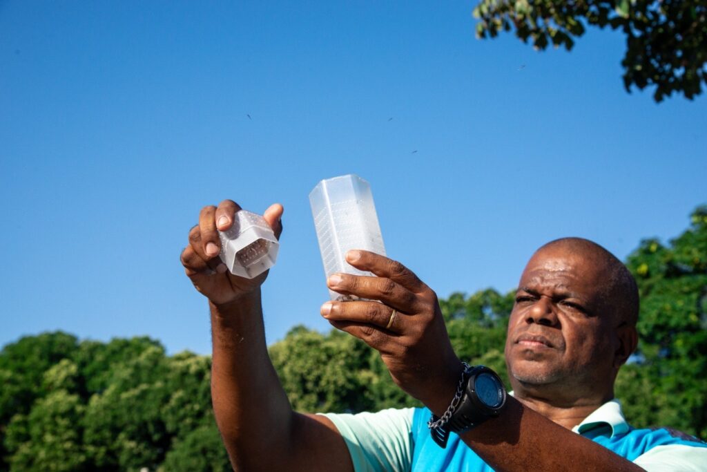 Imagem homem abrindo recipiente com mosquitos para serem soltos