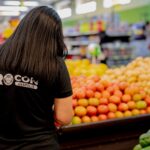 Imagem mulher com camisa preta do Procon na frente tem tomate, batata, chuchu