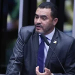 Imagem Wanderley Barbosa falando ao microfone ele está de terno e gravata azul