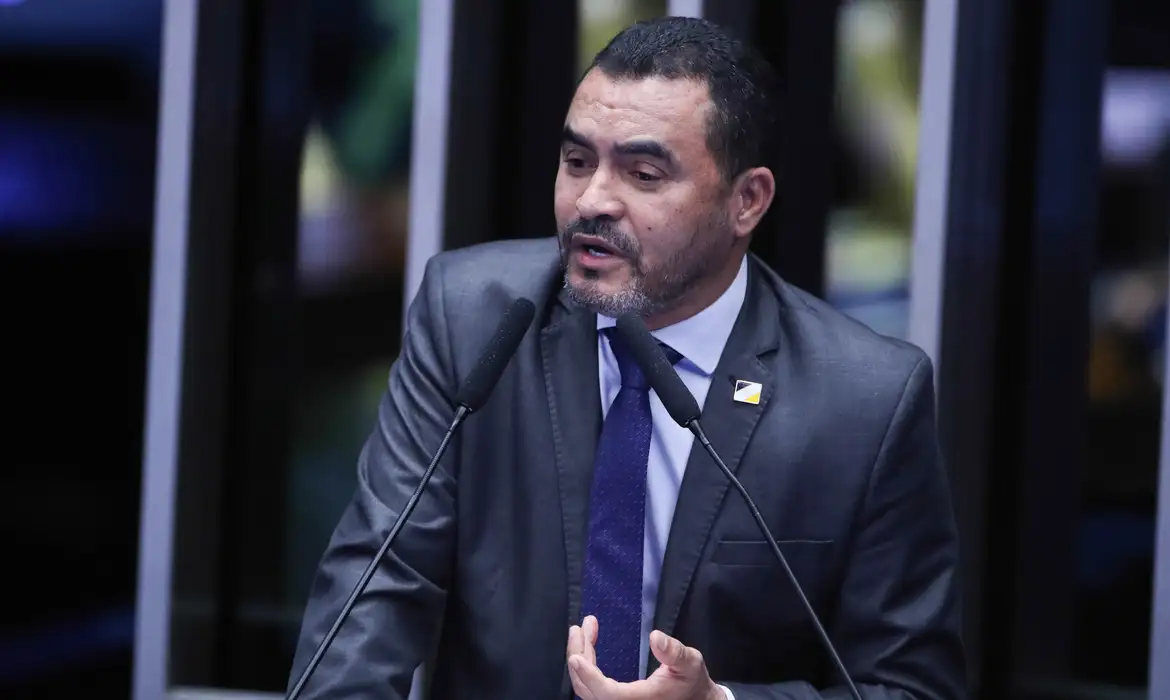 Imagem Wanderley Barbosa falando ao microfone ele está de terno e gravata azul