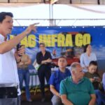 Imagem Daniel Vilela discursando, ele está de camisa branca com a mão direita erguida