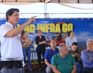 Imagem Daniel Vilela discursando, ele está de camisa branca com a mão direita erguida