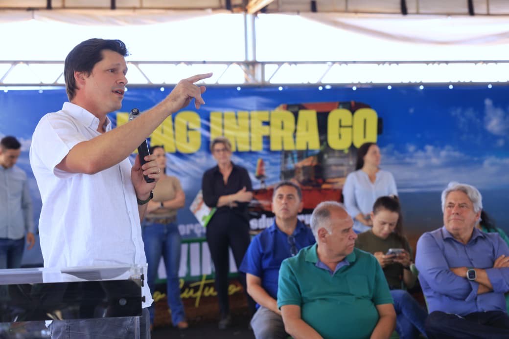 Imagem Daniel Vilela discursando, ele está de camisa branca com a mão direita erguida