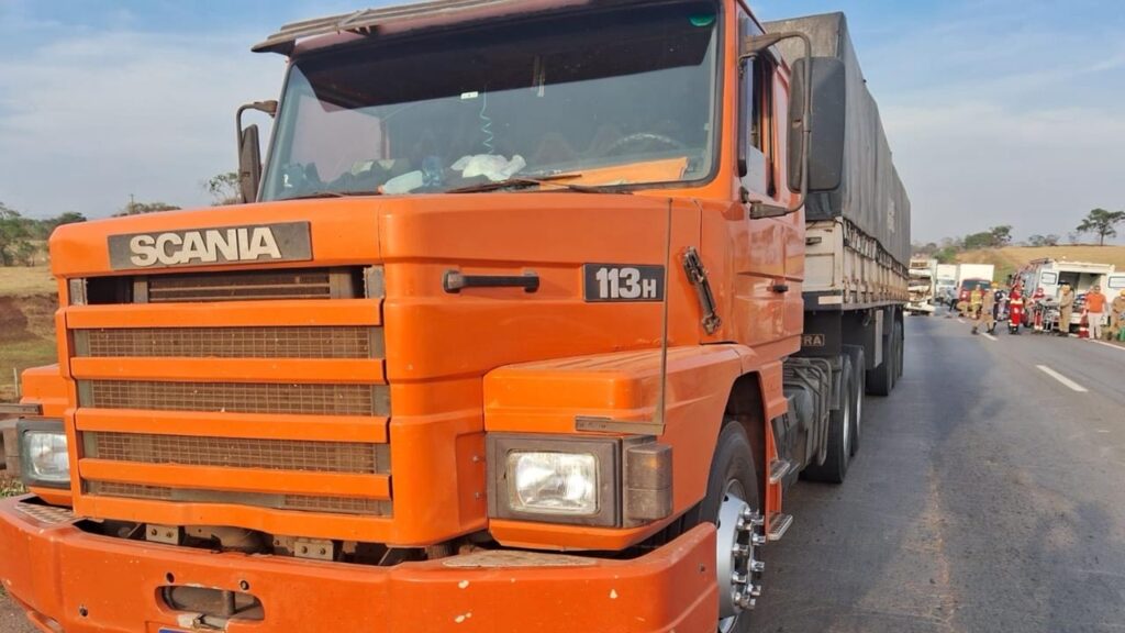 Imagem caminhão cor laranja parado na rodovia