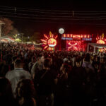Imagem varias pessoas em um show a frente está o palco