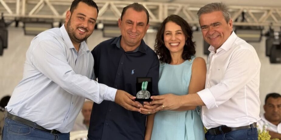 Imagem quatro pessoas sorrindo segurando um pequeno troféu de homenagem