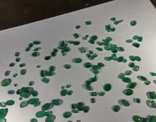 Imagem várias esmeraldas verdes sobre uma superfície branca