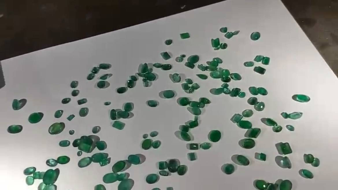 Imagem várias esmeraldas verdes sobre uma superfície branca