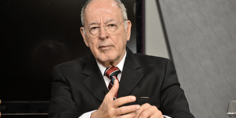 Imagem Irapuan Costa Júnior, de terno preto e gravata com detalhes em vermelho