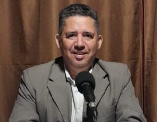 Imagem homem sorrindo em frente do microfone