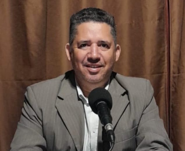 Imagem homem sorrindo em frente do microfone