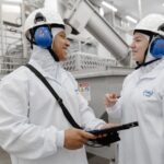 Imagem pessoas de roupas brancas e capacete com tapadores de ouvido cor azul