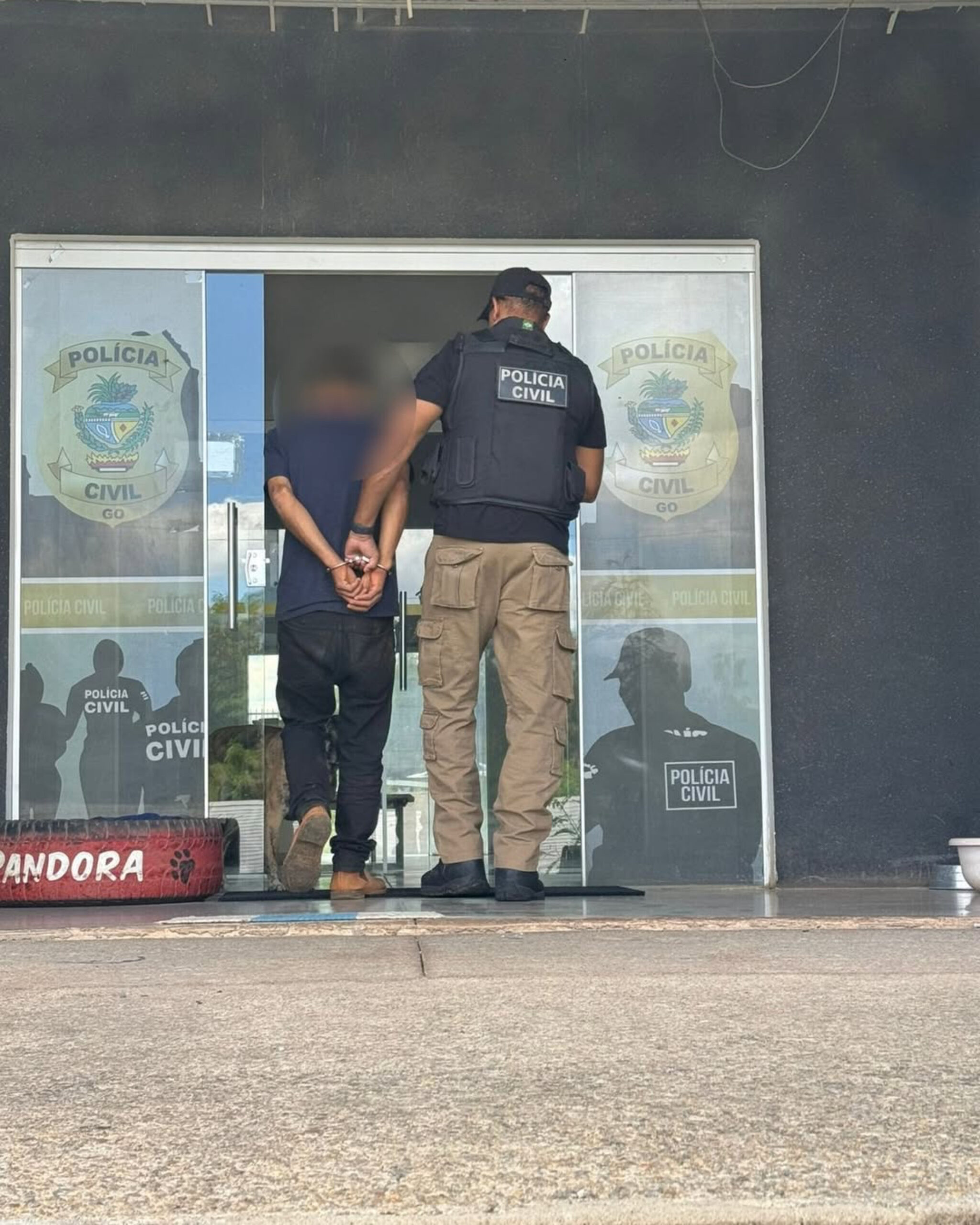 Imagem policial conduzindo homem algemado