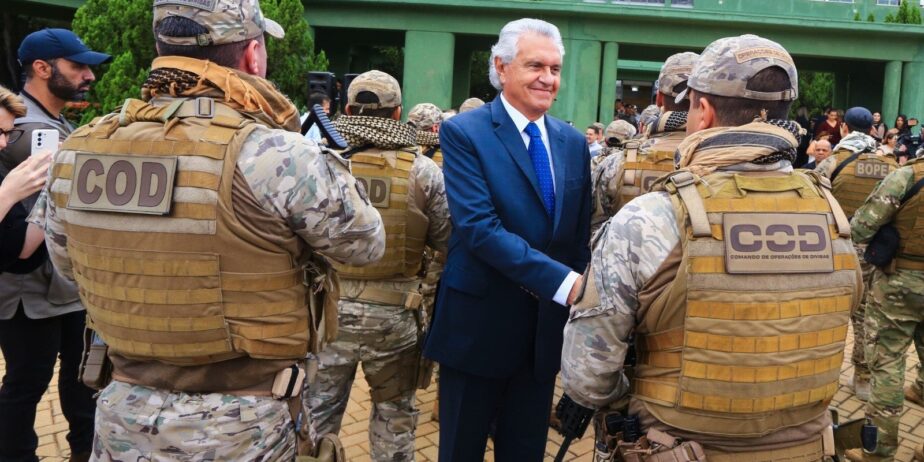 Imagem homem de terno cumprimenta policiais militares