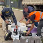 Imagem policiais e agentes fiscalizando mercadoria de vinho