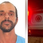 Imagem homem de barba e camisa azul ao lado uma ambulância de SAMU