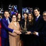 Imagem pessoas segurando troféu e sorrindo para foto