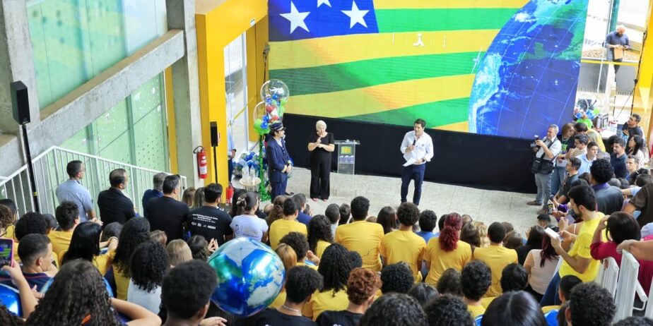 Imagem publica em teatro lotado a frente um homem fala ao microfone