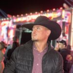 Imagem homem de chapéu e jaqueta preta olhando para o lado