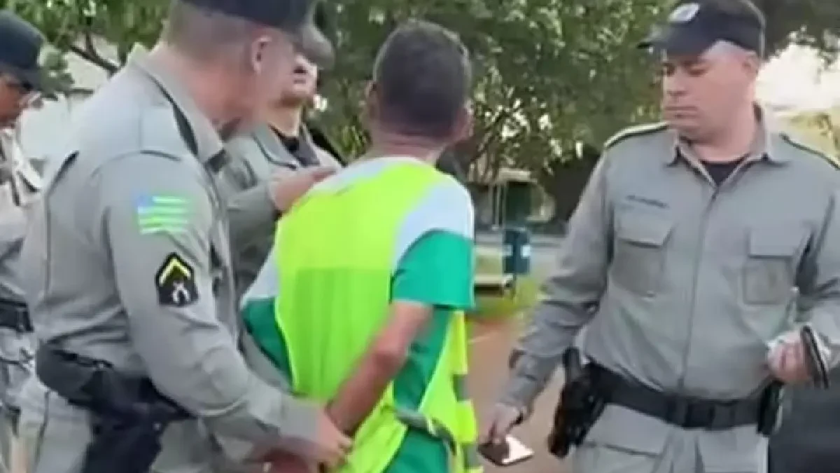 Imagem homem colete verde sendo conduzido pela policia