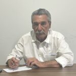 Imagem homem de bigode e camiseta branca segurando caneta