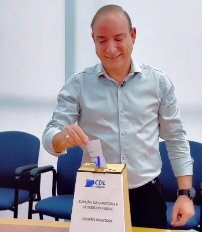 Imagem homem sorrindo colocando voto na urna