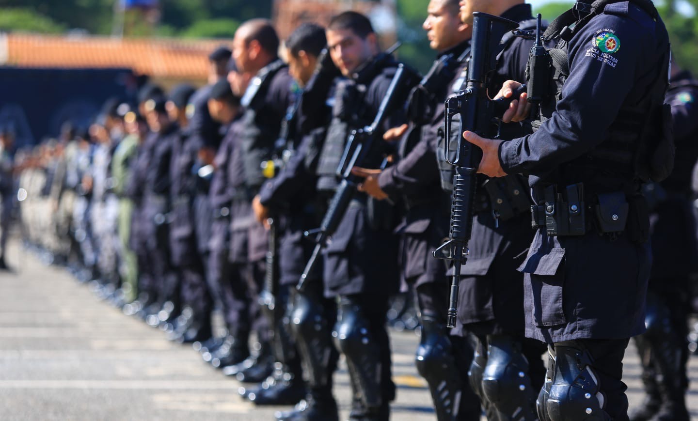 Imagem policiais de farada preta segurando arma longa